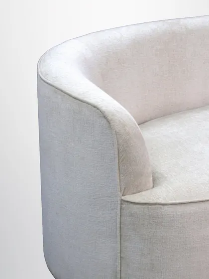 A detail of the curved sofa, showing its seamless upholstery and gentle arc. This design provides a soft, enveloping feel, making it as comfortable as it is stylish.