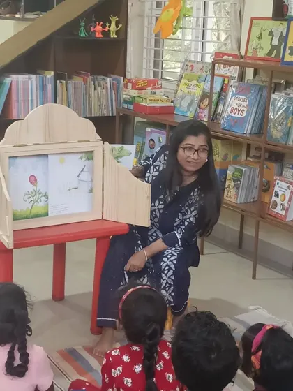 A smiling storyteller engages with her audience while using the story box. Her warmth and enthusiasm are contagious, making every child feel welcome.