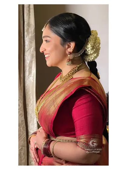 A side profile of Chinvatha, showcasing her simple and elegant bridal hairstyle. The classic bun with fresh flowers is a timeless choice that perfectly complements a traditional South Indian wedding look.