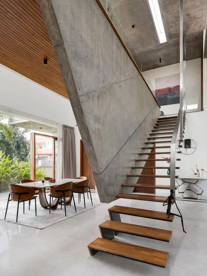 The sculptural, angular concrete wall and floating staircase at The Quarry House, viewed from the dining area.