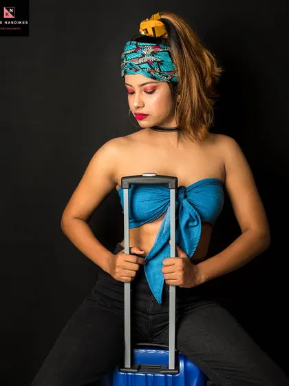 Another take from the 'Caribbean Tourist' concept. The model holds onto the suitcase handle, her pose suggesting she's ready for an adventure, blending travel themes with studio fashion.