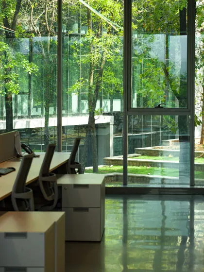 An office space at the Amara Raja campus with desks positioned to offer direct views of the terraced gardens outside. This connection to nature is proven to reduce stress and enhance employee performance.