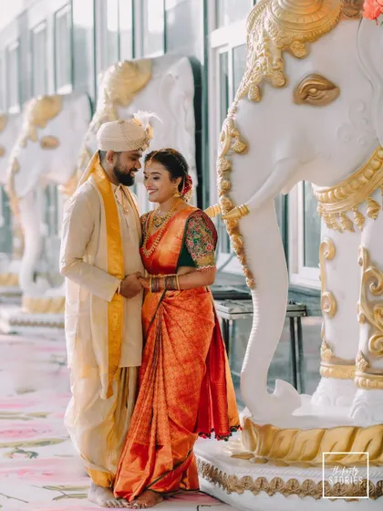 A regal portrait of the couple standing beside ornate elephant statues. This shot combines traditional elements with a touch of grandeur, perfect for a wedding album.