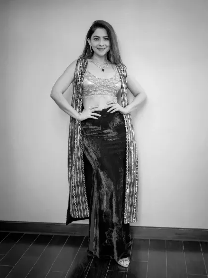 A confident, full-length pose in black and white. This image highlights the model's silhouette and the textures of her outfit against a simple background.