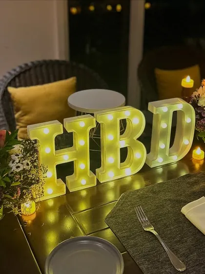 A full view of the birthday table setup. The combination of flowers, candles, and marquee letters creates a warm and festive dining experience.