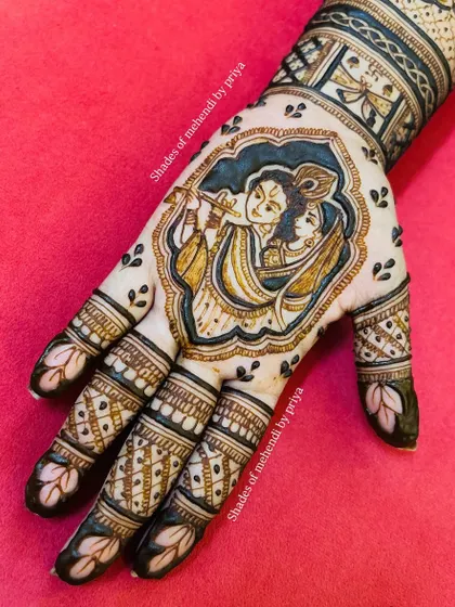 A detailed Radha-Krishna portrait framed within the palm. The use of negative space and intricate line work makes the divine couple the central focus of this beautiful design.