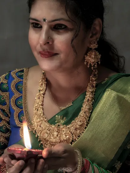 A Diwali look featuring a rich green silk saree and a custom-designed blouse with peacock feather embroidery. The antique gold jewelry adds a touch of royal elegance.
