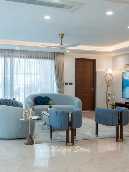 The foyer of this modern apartment features a floating marble TV wall with integrated shelving for plants and decor. The design creates a stunning first impression while being highly functional.