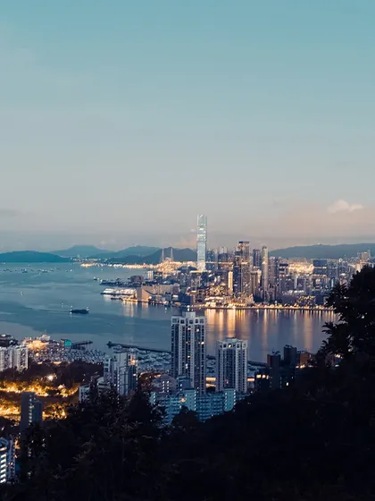 The Hong Kong cityscape just after sunset, during the "blue hour." The city lights begin to twinkle, creating a beautiful transition from day to night.