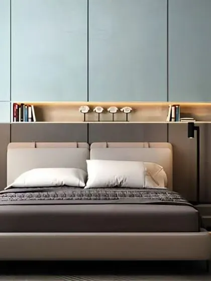 A modern bedroom with a sleek, integrated headboard that includes a bookshelf and built-in reading lights. The high-gloss blue panels above add a touch of color and sophistication.