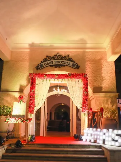 A classic red carpet entrance for the 'MAISHA' wedding reception at Club Exotica, Madh. We framed the doorway with red floral arrangements and placed a large marquee sign with the couple's hashtag.