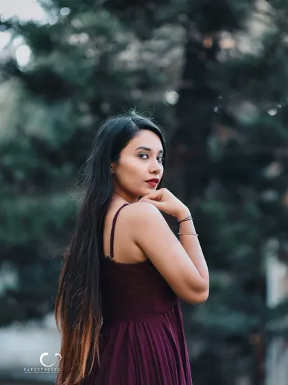 A classic over-the-shoulder glance. Her expression is confident and alluring, and the natural setting provides a beautiful backdrop.