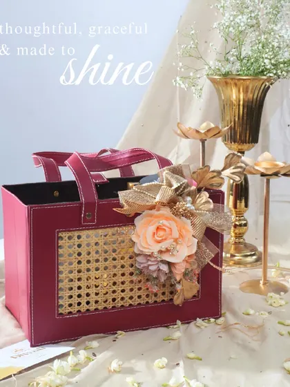 This radiant hamper in a deep red leatherette and cane bag is designed to shine. It's a thoughtful and graceful gift, adorned with a peach floral arrangement, perfect for lighting up your Diwali celebrations.