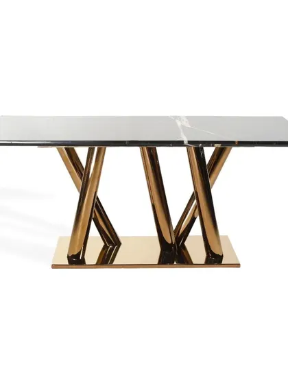 A standalone view of the dining table with a black marble top and a sculptural, crisscrossing PVD gold base. This piece is designed to be a functional work of art.