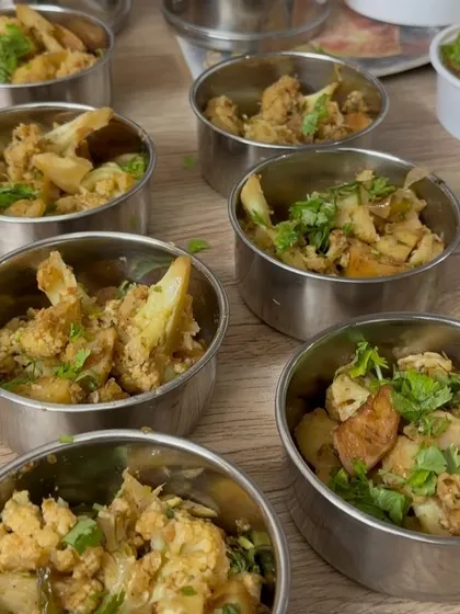 Freshly made Aloo Gobi being portioned into steel tiffin containers. We use these traditional tiffins for our regular subscribers to ensure a sustainable and authentic experience.