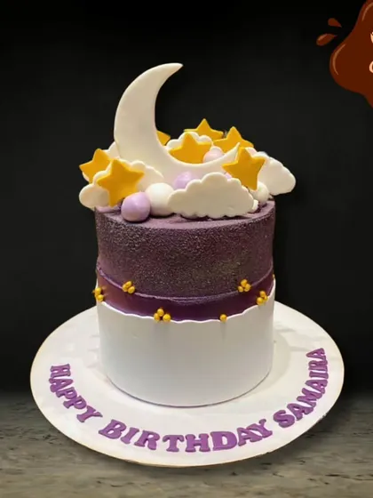 A beautiful and serene cake featuring a crescent moon and golden stars nestled in fluffy white clouds. The purple and white design creates a dreamy night sky effect.
