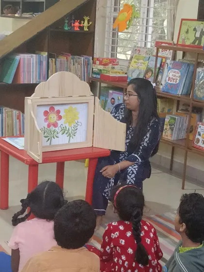 The storyteller pauses to let the children absorb the illustration in the story box, encouraging visual literacy.