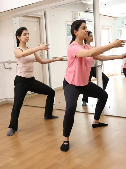 Two members perform a plié at the barre, a foundational move in our energetic and effective ActivBarre classes.