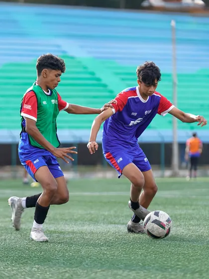 Two players engage in a one-on-one duel for the ball. These competitive drills are essential for developing both attacking and defensive skills.