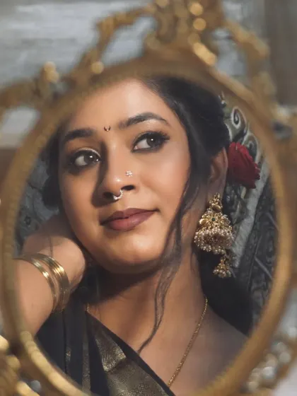 A reflection in a vintage mirror. This shot captures the essence of the retro look, with classic jhumkas, a simple bindi, and a red rose in my hair.