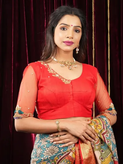 A model pairs a vibrant red blouse with a simple, elegant choker and bracelet. This shows how minimalist jewellery can beautifully accessorize a brightly colored outfit.