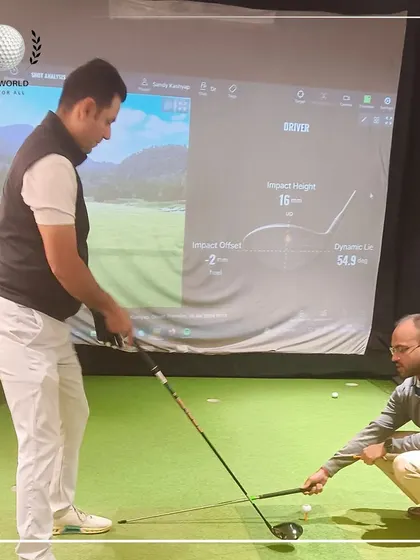 I'm demonstrating the correct setup to a client, with his swing data visible on the simulator screen. This is a perfect example of combining practical coaching with technology.