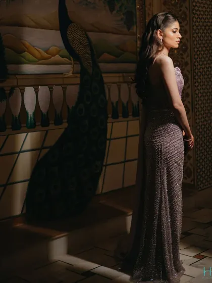 An elegant bridal portrait, with the bride looking away from the camera, showcasing the silhouette of her gown against a beautifully painted wall.