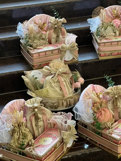 A collection of beautiful wedding invitation hampers, designed in a delicate pink and gold theme. Each hamper is thoughtfully arranged in ornate trays, ready to be sent to loved ones.