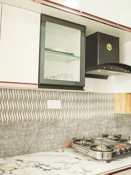 A wider view of the kitchen with the grey textured backsplash. The combination of white, wood, and grey creates a calm and sophisticated color palette.