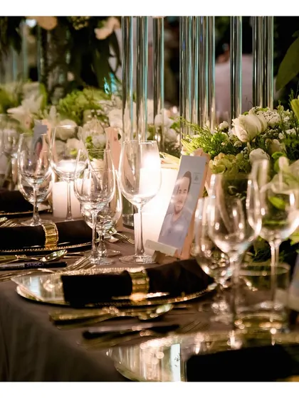 A detailed view of a sophisticated table setting, featuring gold-rimmed charger plates, crisp black napkins, and personalized place cards, reflecting our meticulous attention to detail.