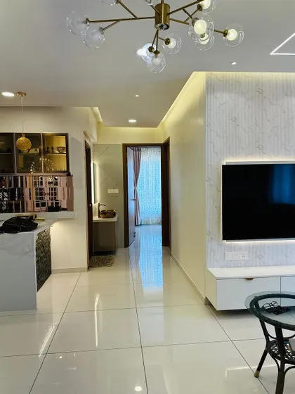 A wide shot of the living and dining area, showing the open layout and consistent design theme. The glossy tiled floors and modern lighting make the space feel bright and expansive.