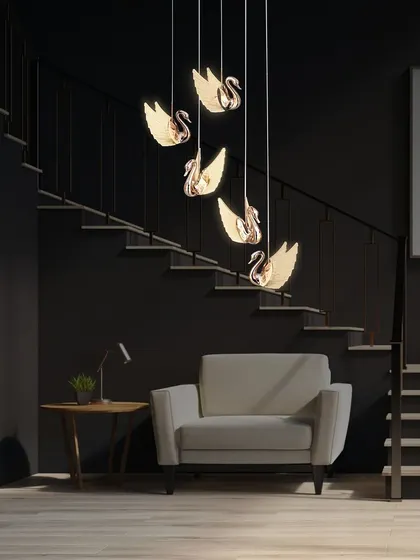 The swan chandelier looks stunning against a dark staircase, creating a dramatic and luxurious focal point.