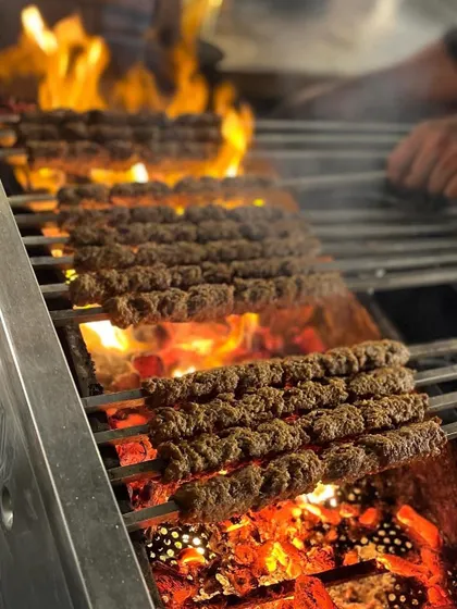 Rows of mutton seekh kebabs sizzling over a fiery charcoal grill, showcasing the authentic cooking process.
