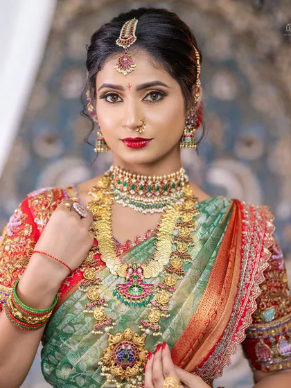 A stunning close-up of a bride wearing a layered kemp and Kasu Mala set. The intricate details and vibrant colours make this a very popular choice for hire.