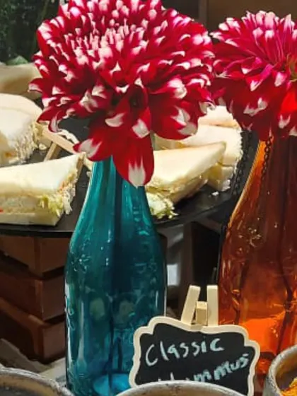 The vibrant floral arrangements in colorful bottles were a key part of the decor for this corporate wine and cheese event. They added a pop of color to the sophisticated spread of sandwiches and hummus.