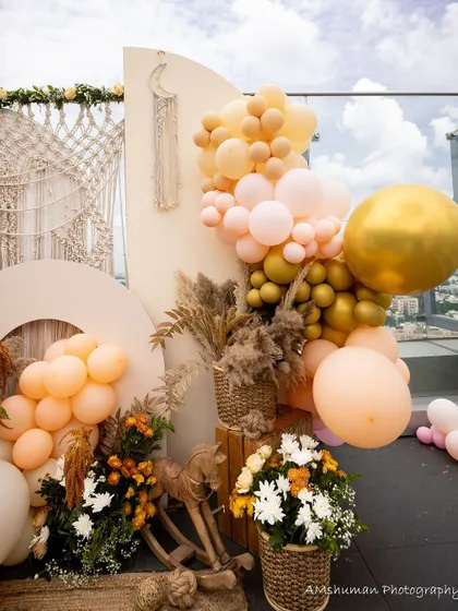 A rooftop boho baby shower setup. The decor features a beautiful balloon garland, pampas grass, and woven baskets, all set against a stunning city skyline.