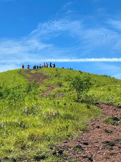 The trail leading up to the Kodachadri peak, with trekkers visible on the summit under a clear blue sky.