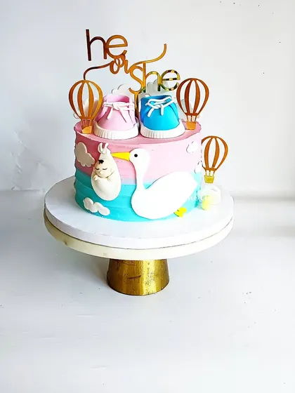 He or She? A fun and colorful gender reveal cake! This design features pink and blue baby shoes, a stork carrying a baby, and hot air balloon toppers.