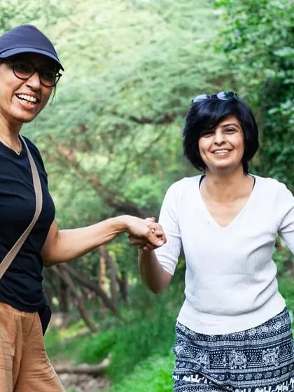 Two volunteers share a happy moment during a nature walk, holding hands and smiling as they explore the restored Aravali Creek.