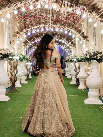 A back view of the client in the same lehenga, set against a beautiful floral archway.