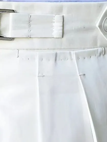 A detailed view of the waistband on our white trousers, showing the precise stitching and construction of the side adjuster.