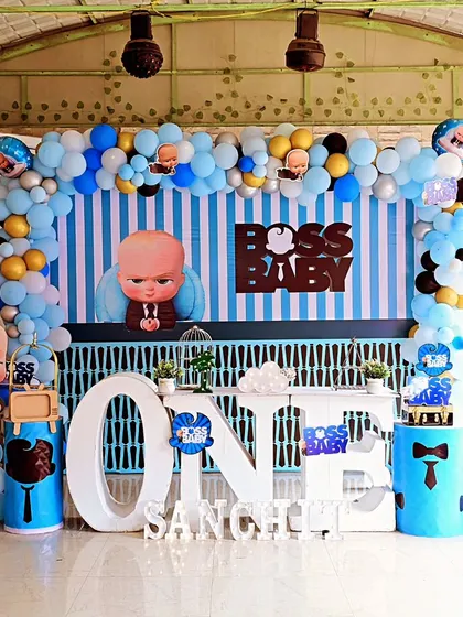 Here is another angle of our Boss Baby theme for Sanchit's first birthday. The setup includes a striped backdrop, a large "ONE" table for the cake, and character cutouts, all framed by a beautiful balloon garland. Note: This is the same setup as ID 176.