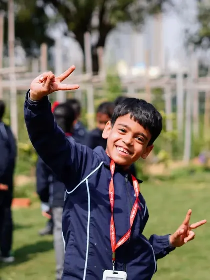 A smiling student gives a peace sign to the camera, clearly enjoying his school trip.