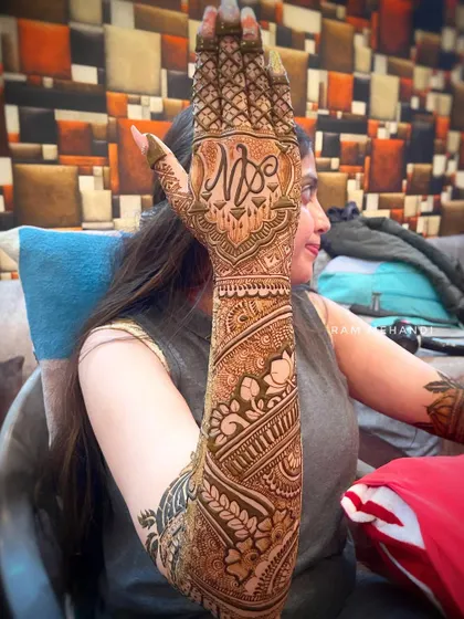 A full-arm bridal design shown from the side. This view highlights the seamless flow of patterns from the wrist to the elbow, featuring a custom initial monogram on the back of the hand.