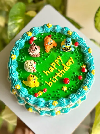 Pokémon dream cake alert! This custom cake features edible Pokémon characters like Pikachu and Charmander crafted with buttercream, sitting on a vibrant green field.