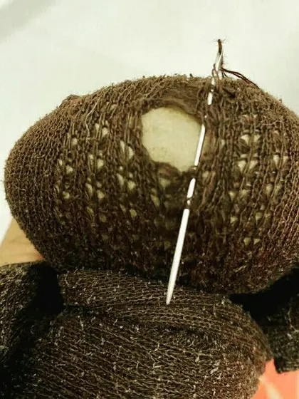 A close up of a sock being darned. This traditional mending technique is a simple, effective way to extend the life of clothing and reduce waste, one sock at a time.