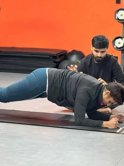Correcting form during a plank is essential for effectiveness and safety. A trainer makes a minor adjustment to a client's posture to maximize core engagement.