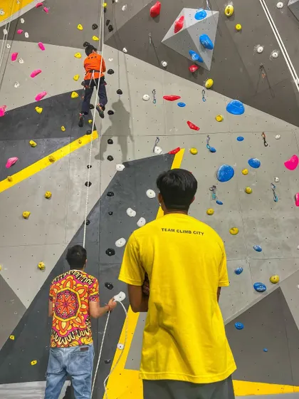 An instructor watches over a climber on our top-rope wall, ensuring safety and providing encouragement. Our "Learn to Climb" sessions are perfect for beginners to understand the basics of rope climbing in a controlled setting.