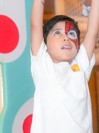 A boy with a cool Spider-Man face painting looks up, ready for more party fun.