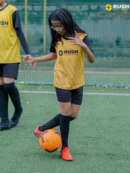 A young female player demonstrates excellent ball control. We are committed to providing a supportive environment for girls to develop their football skills and passion.